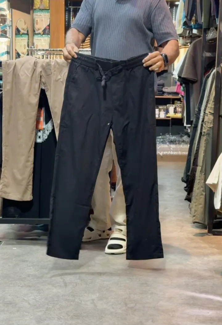 Black linen drawstring trousers held up in the store, a beige pair on the rail