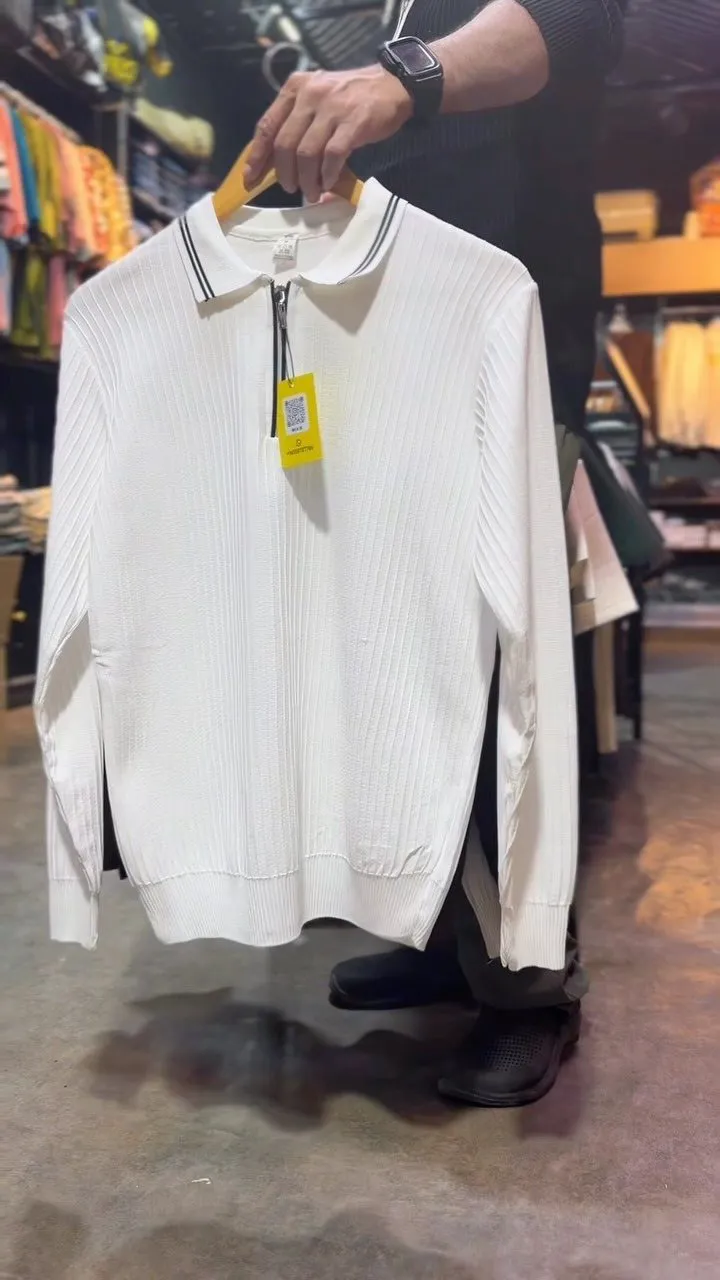 White ribbed half-zip knit polo with a black-tipped collar on a hanger in the store