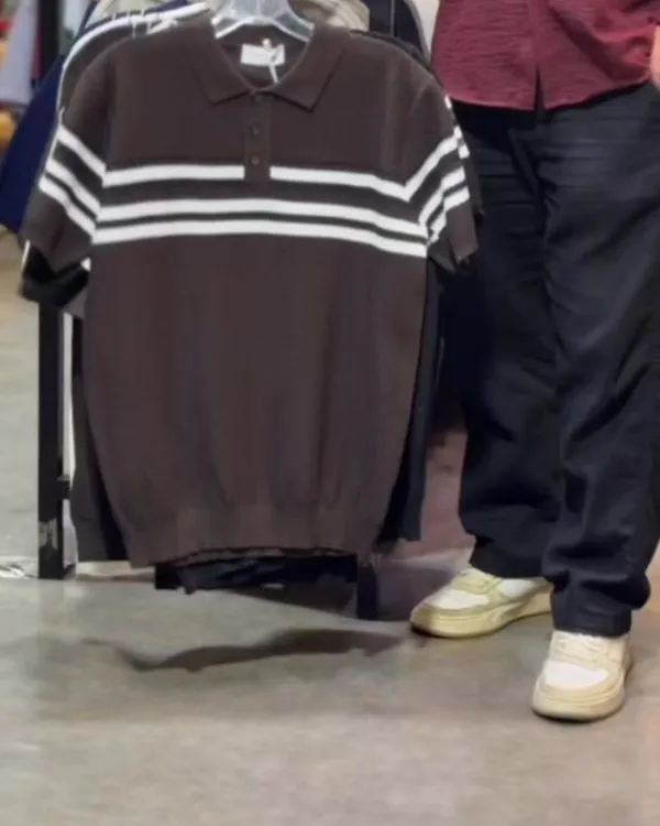 Close-up of the striped knit polo on its hanger