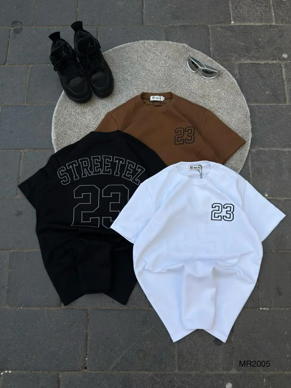 Black tee with a Streetez 23 back print beside brown and white number tees